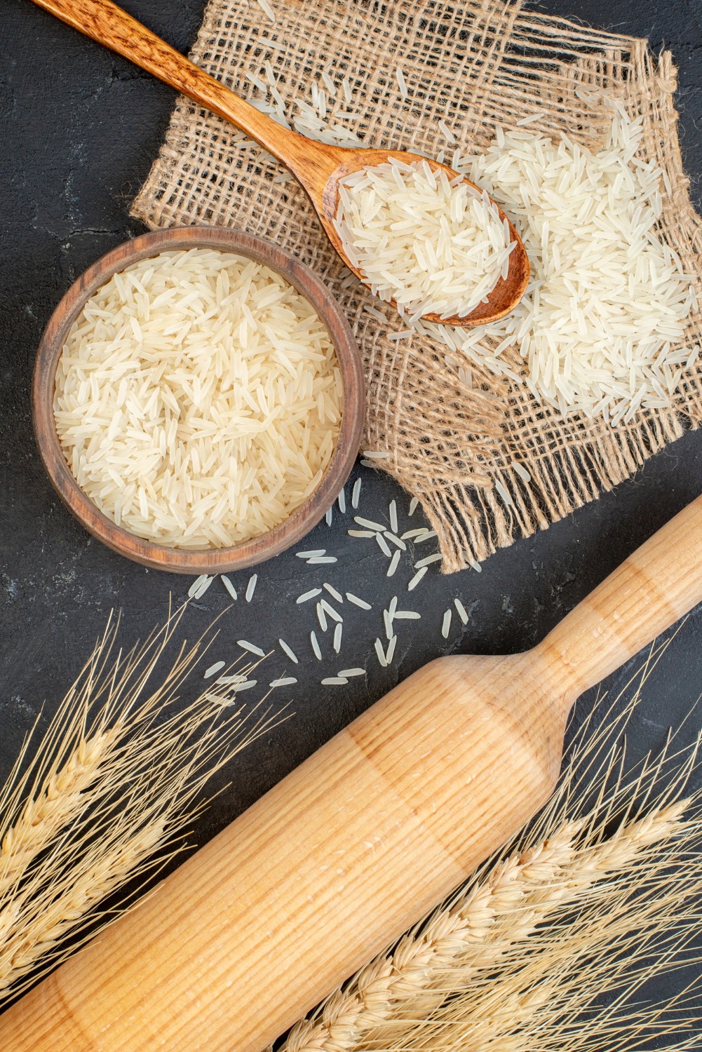top-view-rice-bowl-wooden-spoon-rolling-pin-black-table